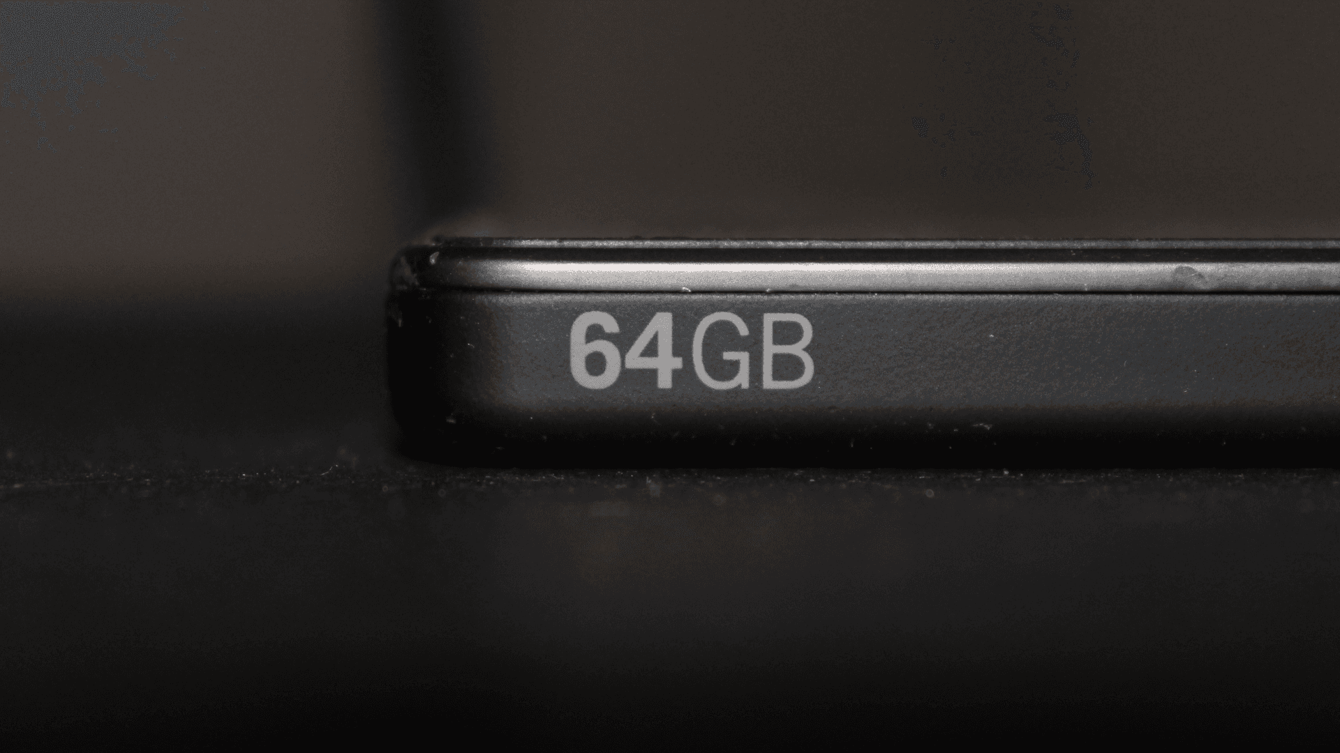 Primer plano del canto de un teléfono móvil negro con la inscripción 64GB serigrafiada.