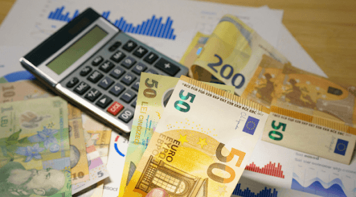 Billetes de euro junto a una calculadora que representan el cálculo del gasto en la factura de la luz